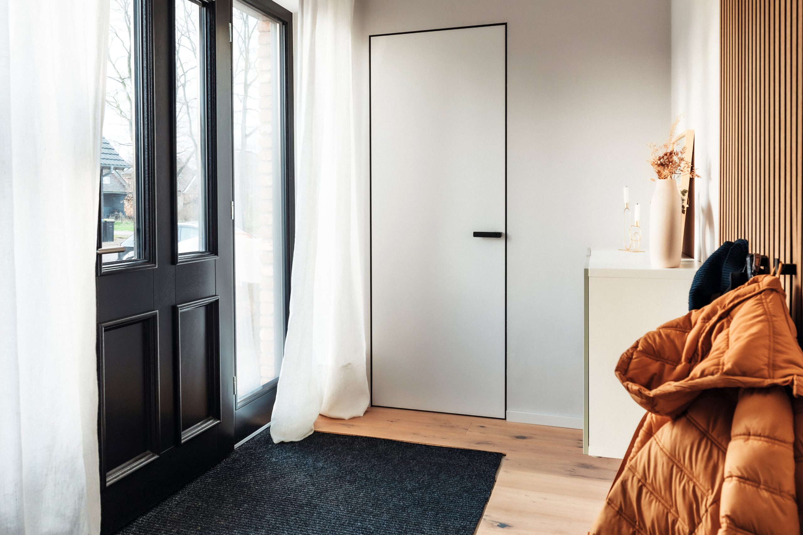 Wohnküche_mit_wandbündiger Tür und einer 6 mm schmalen Zarge. Die Tür ist weiß und der Drücker und die Zarge schwarz.